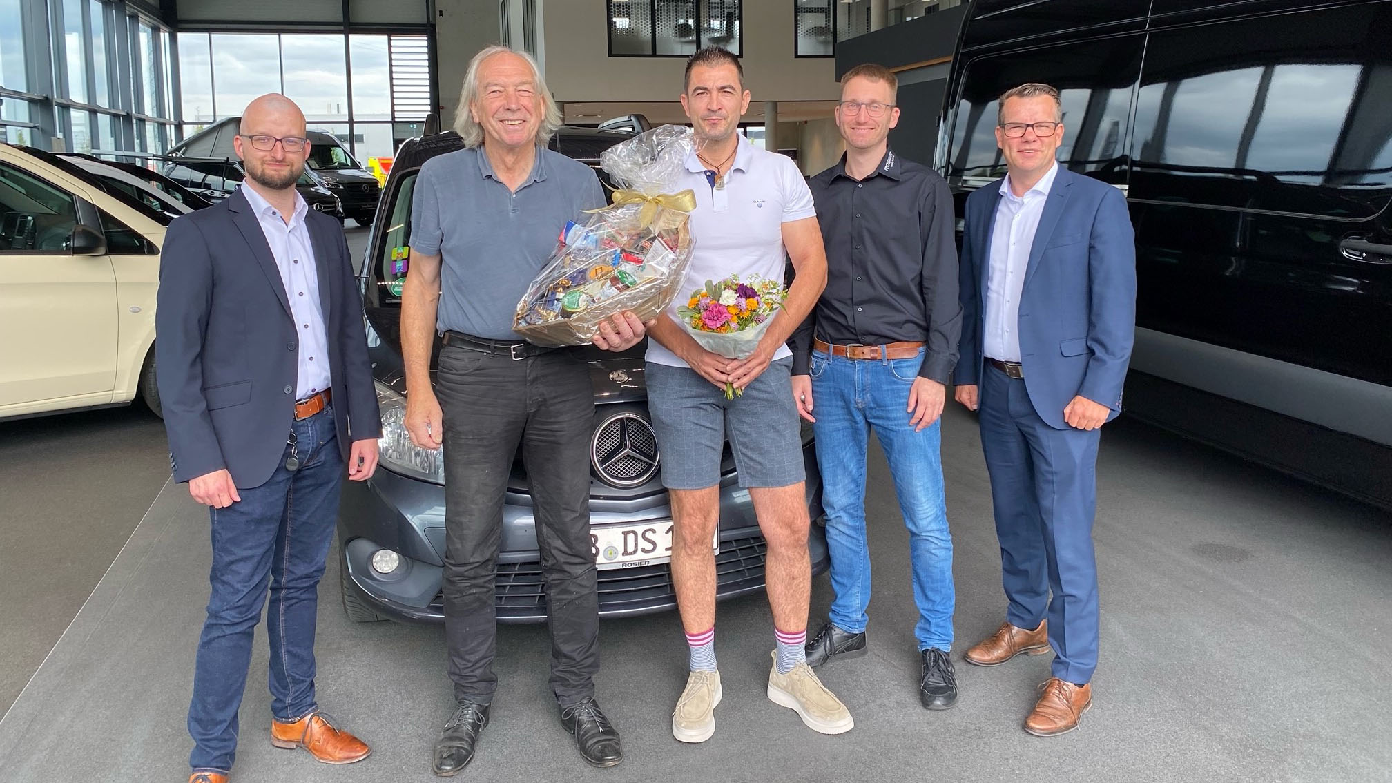 Gruppenbild mit Mitarbeitern und Kunden vom Autohaus Rosier mit Blumenstrauß.