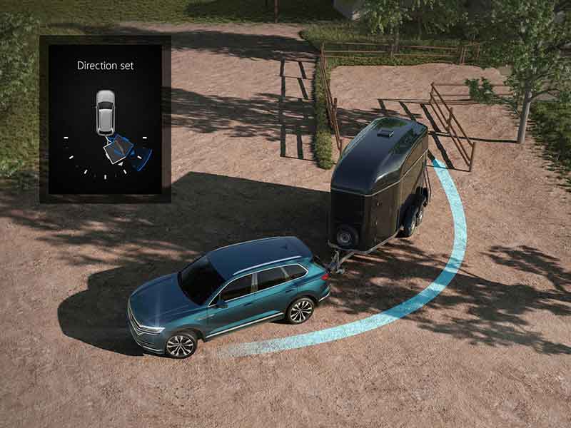 Darstellung der Funktion des Volkswagen Trailer Assist. Ein Fahrzeug navigiert seinen Anhänger dank Systemhilfe rückwärts in eine Lücke.